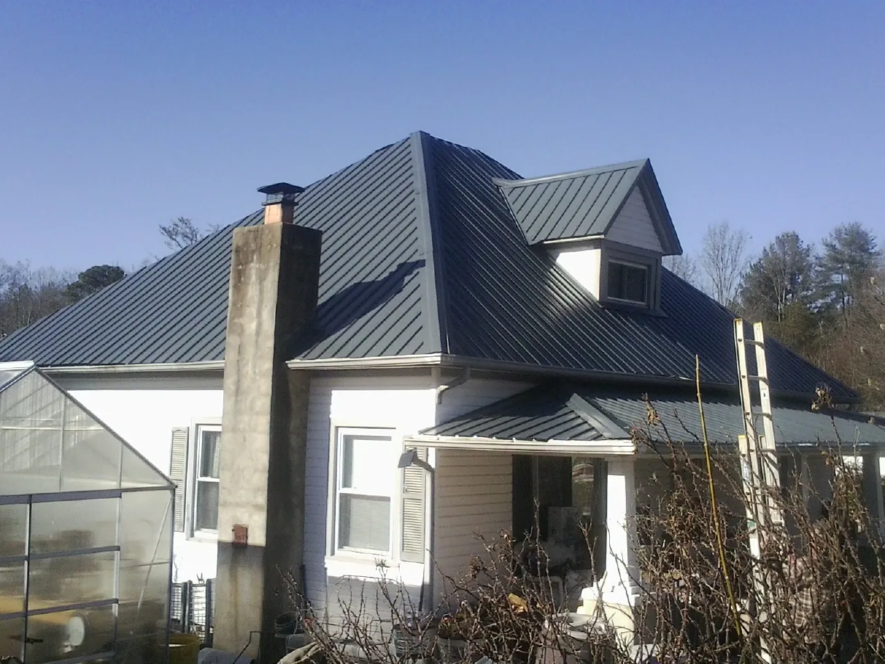 Dark blue standing seam metal roof on a white farmhouse with dormer — Slate & Tile Roof Repair by Roofing Brothers in Brandy Station