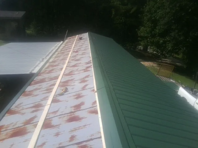 Old rusted panels beside newly installed green metal roofing — Wind Damage Roof Repair by Roofing Brothers in Brandy Station