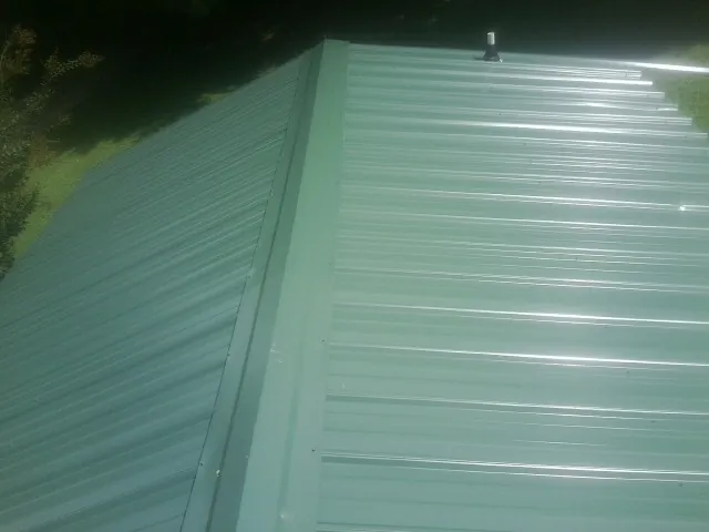 New green metal panels meeting at the ridge of a roof — Flat Roof Repair work by our crew in Brandy Station