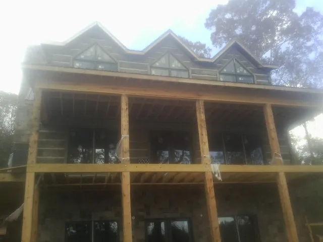 Dormers and porch framing on a large log home under construction — Roof Coating work by our crew in Brandy Station