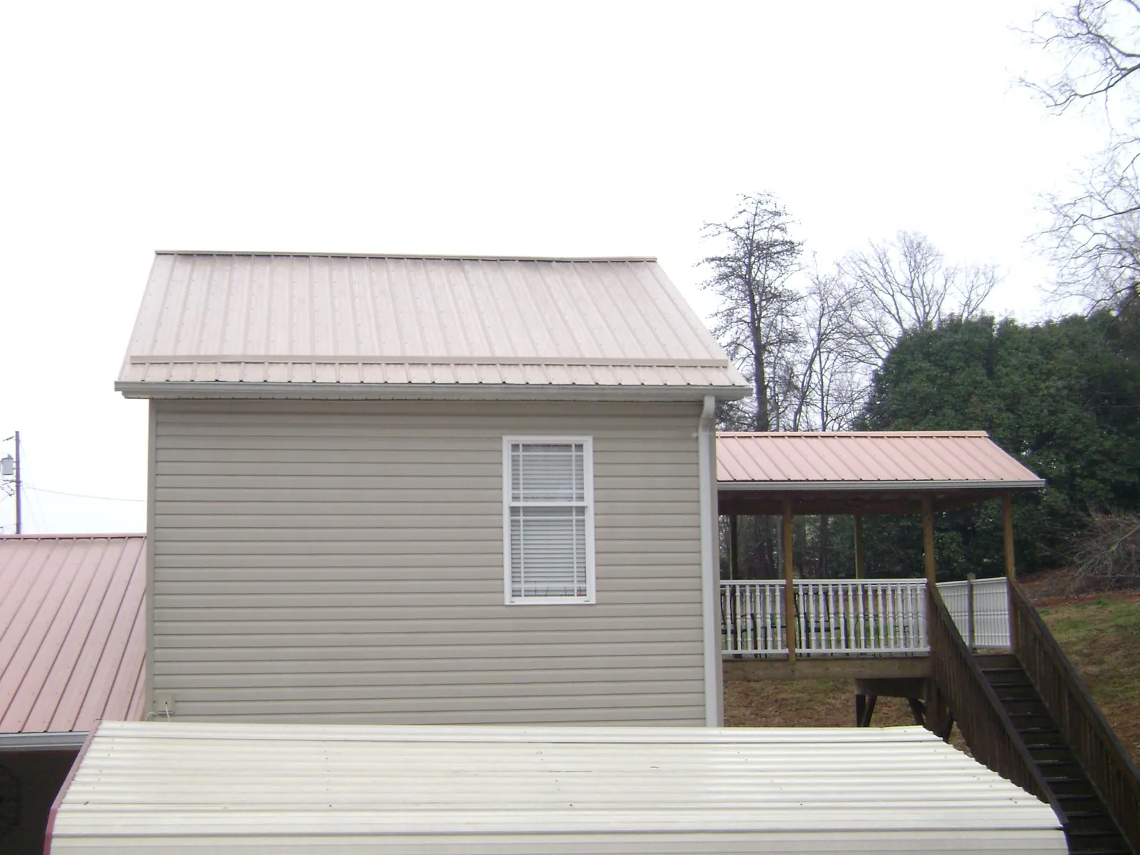 Tan metal roofs on a two story addition and attached porch, from a Roof Replacement job in Brandy Station
